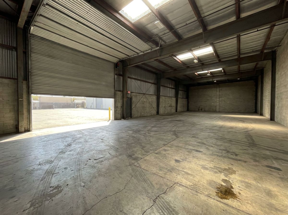 Worn dusty concrete slab in large warehouse bay before epoxy